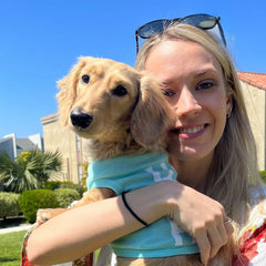 Crystal, founder of Green Paw Wellness, holding her mini dachshund Marley